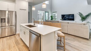 A modern kitchen with a built-in island, stainless steel appliances, and pendant lighting. - Poolside Bliss & Epic Game Rooms! Gem in Kissimmee (Kissimmee)