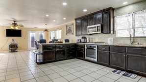 A kitchen with dark cabinets, a microwave, an oven, and a large island. - Wine Country Retreat in Galt w/ Vineyard Views (Galt)