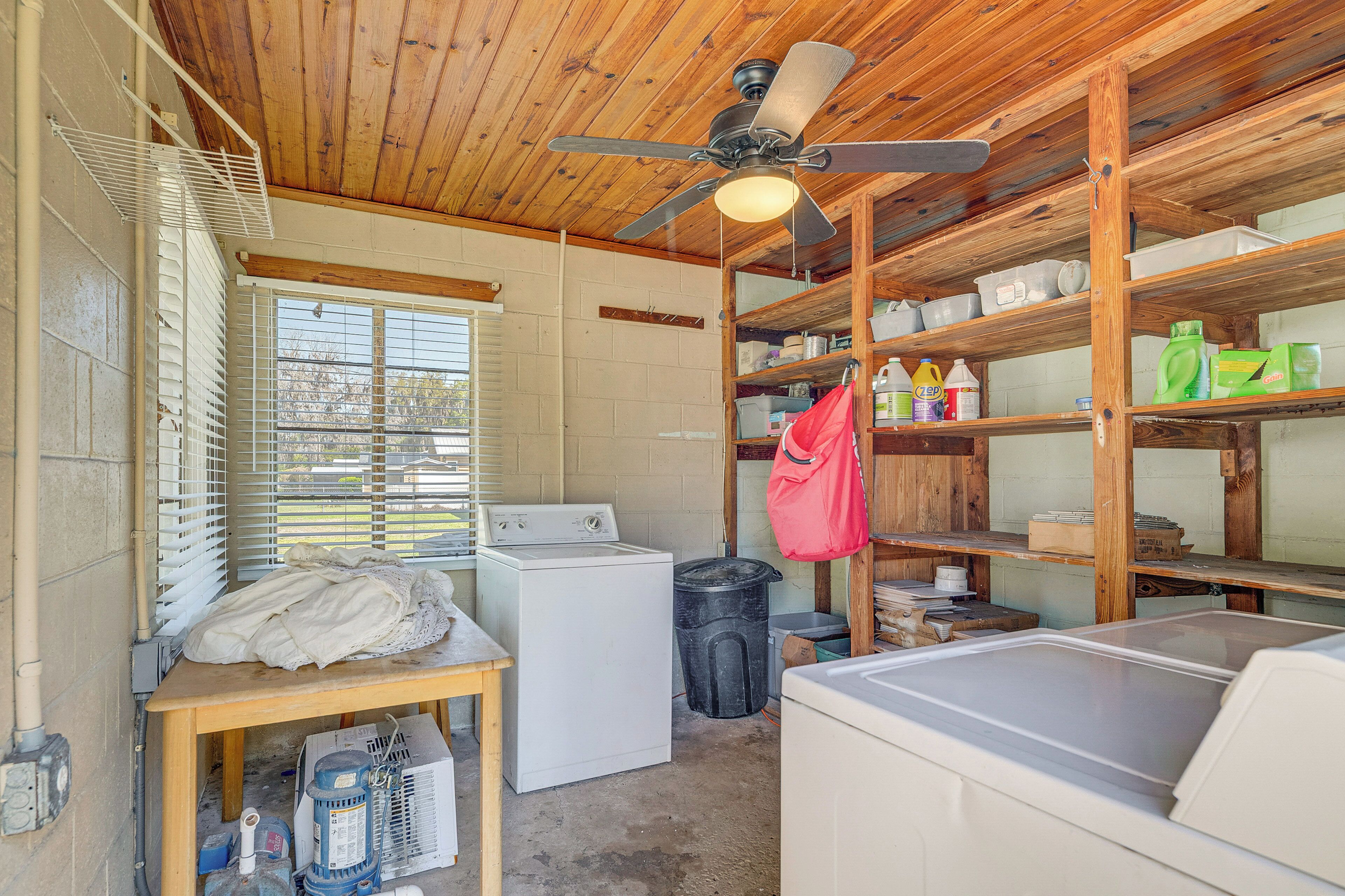 Une buanderie équipée d’un lave-linge, d’un sèche-linge, d’un ventilateur de plafond et d’étagères avec des bacs de rangement.