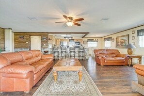 A spacious living room with leather sofas, a wooden coffee table, and a ceiling fan. - Lakefront & Poolside! Family Retreat in Hernando (Hernando)