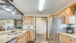 A kitchen with wooden cabinets, a stainless steel refrigerator, a sink, and a coffee maker. - Lakefront & Poolside! Family Retreat in Hernando (Hernando)
