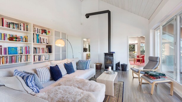 A modern living room with a sofa, bookshelves, a fireplace, and a large window. - Zwergenweg Apartment – 140 sqm, Nature, Tranquility & Stunning Views over the Rhine Valley (Badenweiler)