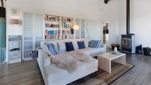 A modern living room with a sofa, bookshelves, a fireplace, and a lamp. - Zwergenweg Apartment – 140 sqm, Nature, Tranquility & Stunning Views over the Rhine Valley (Badenweiler)