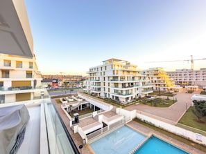Ein moderner Wohnkomplex mit mehreren Balkonen, einem Schwimmbad und Blick auf die Umgebung.