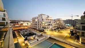 Ein modernes Mehrstöckhotel mit Pool auf dem Dach, Sitzbereichen im Freien und einem gut beleuchteten Innenhof.