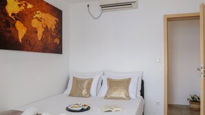 Una camera d'albergo con un letto, una mappa del mondo appesa al muro, un condizionatore d'aria e una porta che dà su un'altra stanza.