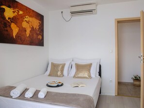 A hotel room with a bed, a world map on the wall, an air conditioner, and a door leading to another room. - Estate With Sea Views Near Omis (Omis)