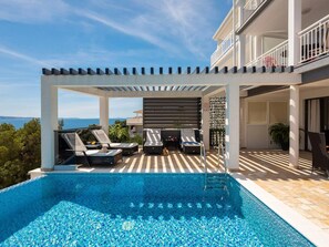 A poolside area with lounge chairs, a pergola, and a view of the sea. - Estate With Sea Views Near Omis (Omis)