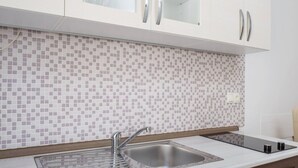 Una cucina moderna con schienale piastrellato, lavello in acciaio inossidabile e pensili in legno.