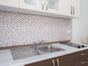 A modern kitchen with a tiled backsplash, stainless steel sink, and wooden cabinets. - Estate With Sea Views Near Omis (Omis)