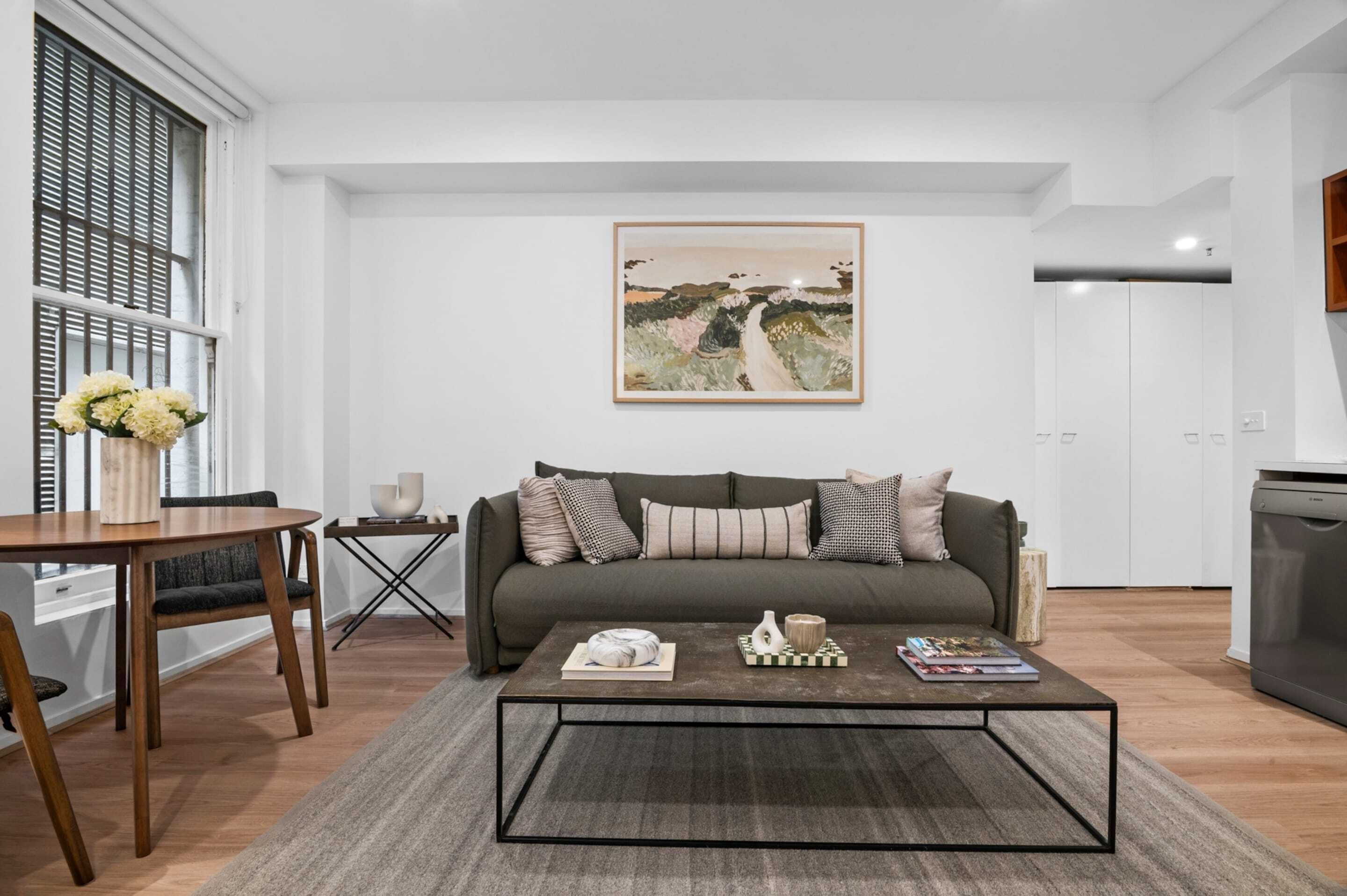 A modern living room with a sofa, coffee table, and artwork on the wall.
