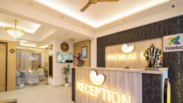 A reception area with a 'RECEPTION' sign, a 'PREMIUM' sign, a ceiling fan, and a 'treebo' logo. - Treebo Premium Inn 62 (Noida)