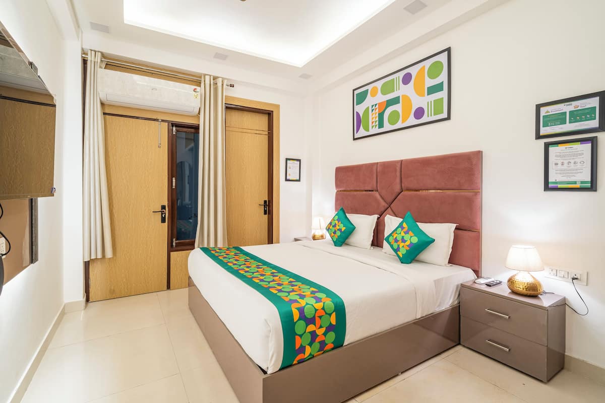 A hotel room with a bed, bedside table, and a ceiling light.