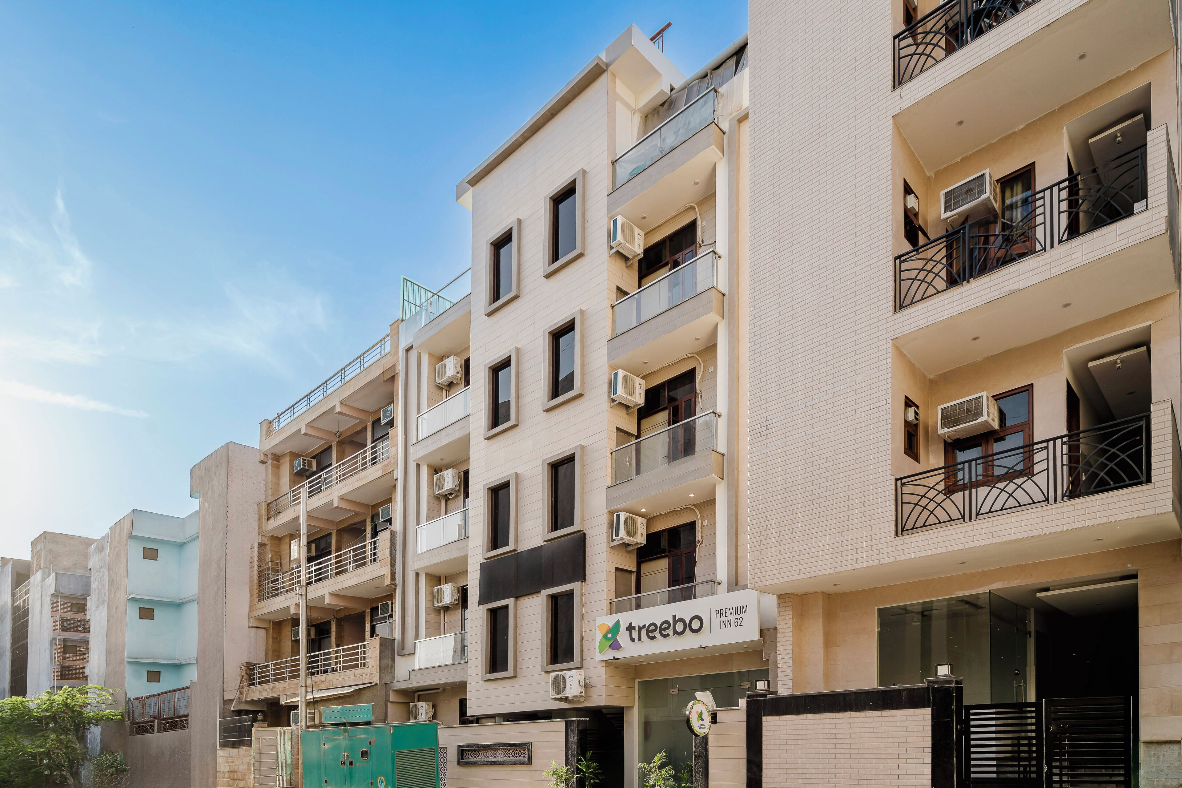 A multi-story hotel with balconies, air conditioning units, and a sign for 'Treebo Premium Inn 62'.