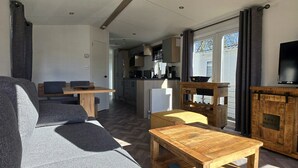 A living room with a sofa, a coffee table, and a television. There is a kitchen area in the background. - Vakantiepark Kijkduin - 838 (Den Haag)