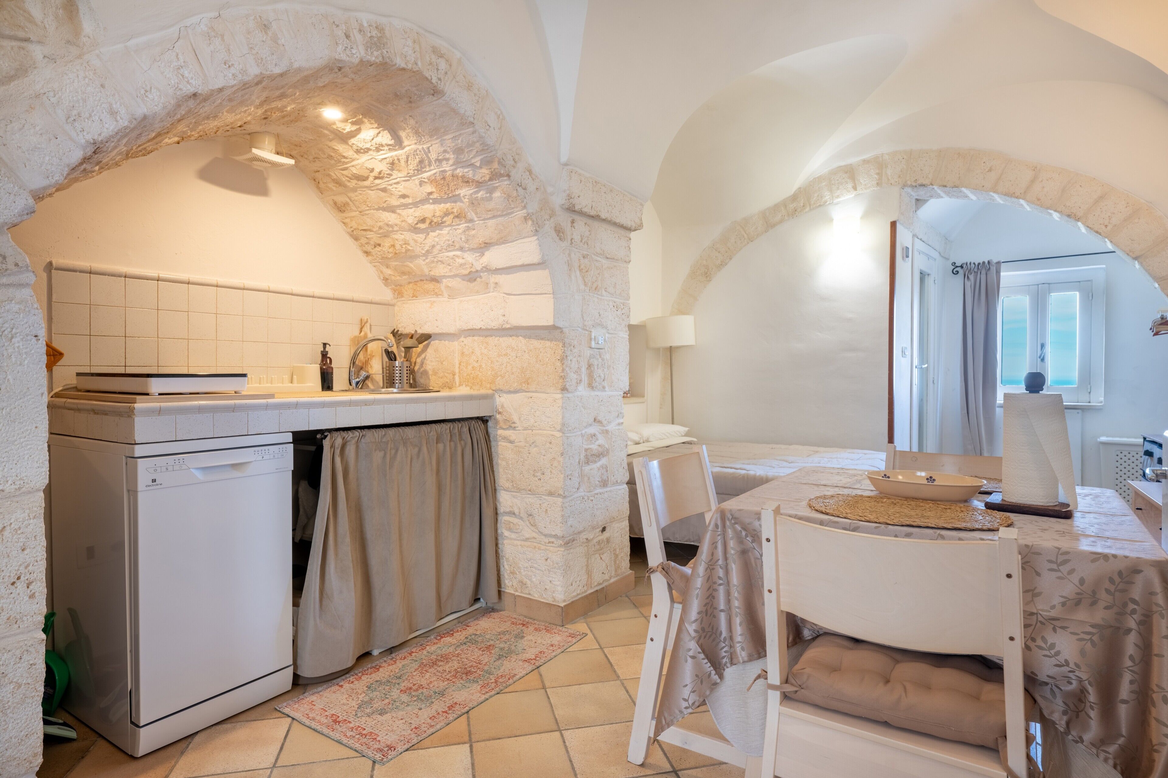 A kitchen with a dishwasher, a sink, and a dining area with a table and chairs.