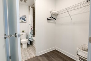 A bathroom with a toilet, a shower, a towel rack, and a hanging shower curtain. - Stylish Downtown Suite With Patio City Views (Kitchener)