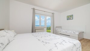 Una camera da letto con un letto, una scrivania, una finestra con tende e vista su del verde.