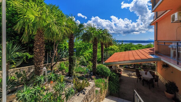 Un'area patio con posti a sedere all'aperto, vista sul mare e diverse piante.