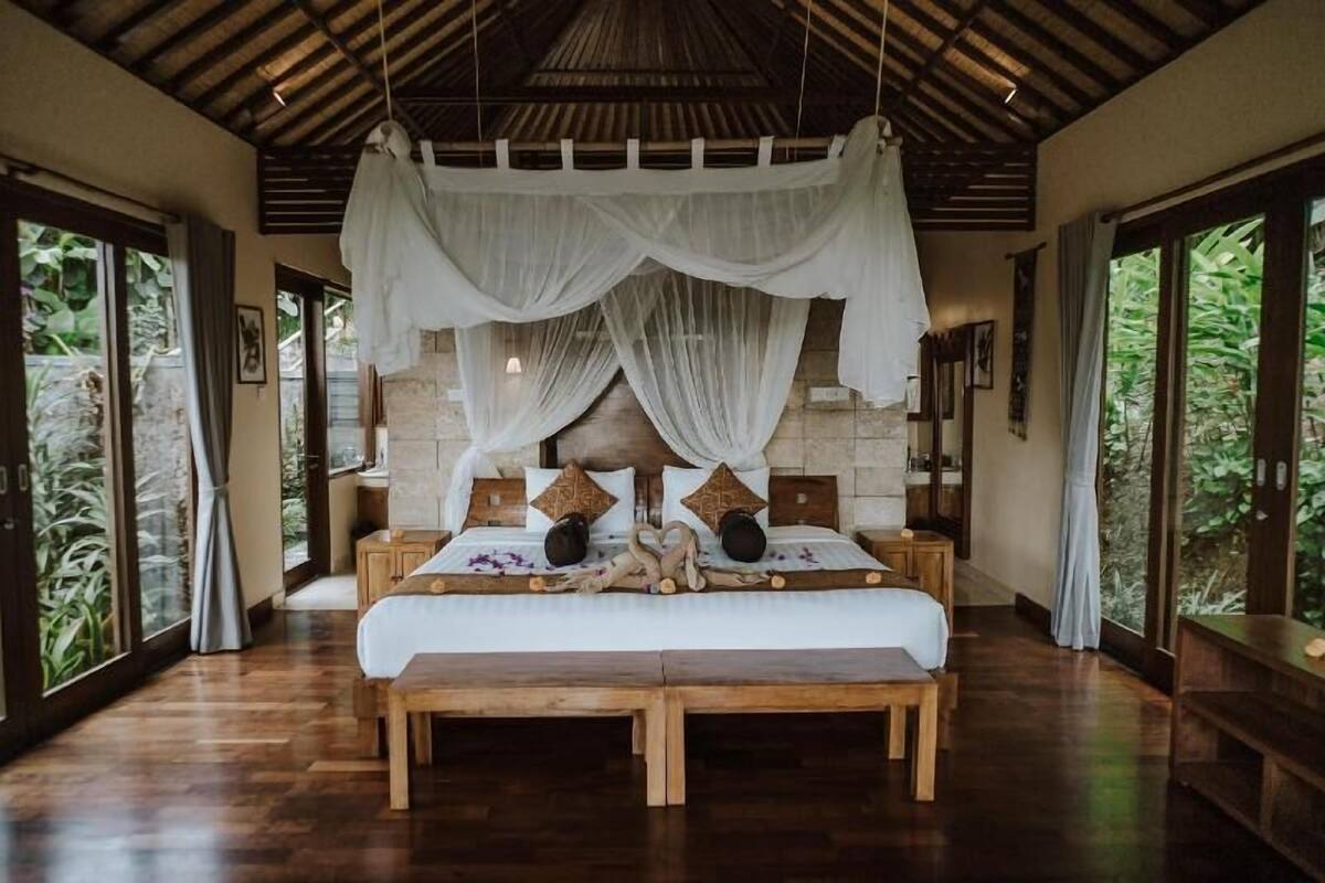 Un grand lit à baldaquin, avec une tête de lit en bois et de nombreux oreillers.