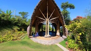 A thatched-roof structure with a central pillar, surrounded by lush greenery. - Munduk Moding Plantation (Gobleg)
