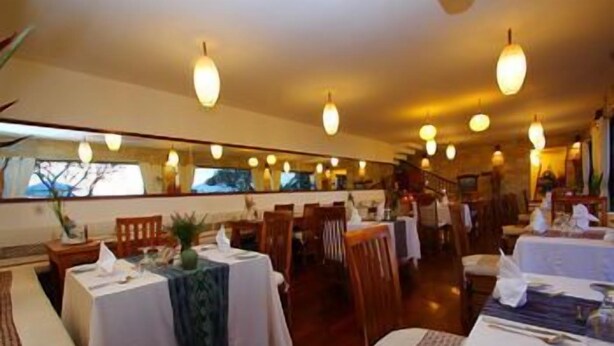 A restaurant with multiple tables, chairs, and hanging light fixtures. - Munduk Moding Plantation (Gobleg)