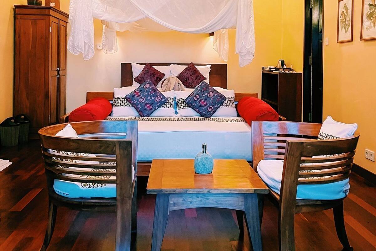 Une chambre à coucher avec un lit à baldaquin, des meubles en bois et un plafond avec des poutres apparentes.