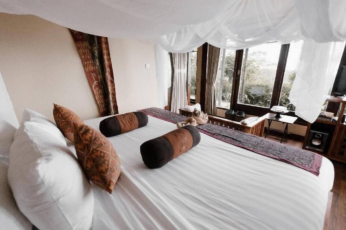Une chambre avec un grand lit, un bureau et une vue sur l’extérieur.