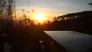 A sunset view from a pool area with a pathway leading to the water. - Munduk Moding Plantation (Gobleg)