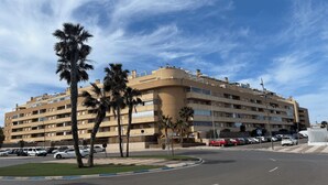 A multi-story hotel with a curved facade, palm trees in front, and a clear blue sky. - MAGNIFICENT PENTHOUSE OVERLOOKING THE POOL (Roquetas de Mar)