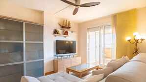 A living room with a sofa, TV, and a ceiling fan. - MAGNIFICENT PENTHOUSE OVERLOOKING THE POOL (Roquetas de Mar)