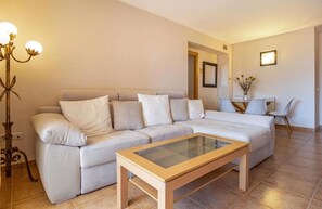 A living room with a sofa, a glass-top coffee table, and a floor lamp.