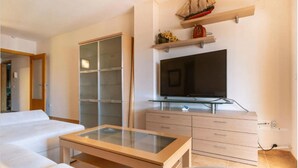 A modern bedroom with a bed, a glass-top coffee table, a TV, and a ship model on the wall. - MAGNIFICENT PENTHOUSE OVERLOOKING THE POOL (Roquetas de Mar)