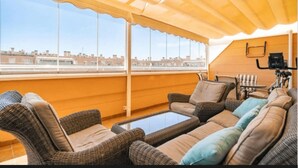 A balcony with wicker furniture, a table, and a ceiling fan. - MAGNIFICENT PENTHOUSE OVERLOOKING THE POOL (Roquetas de Mar)