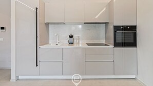 Une cuisine moderne avec des meubles blancs, un four encastré et une machine à café.