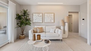 Un salon moderne avec un canapé blanc, une table basse, une plante en pot et des œuvres d’art abstraites accrochées au mur.