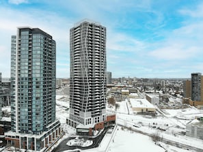 Two high-rise buildings with modern architecture, surrounded by a snowy urban landscape. - Modern High-rise Condo w City Views Balcony (Kitchener)