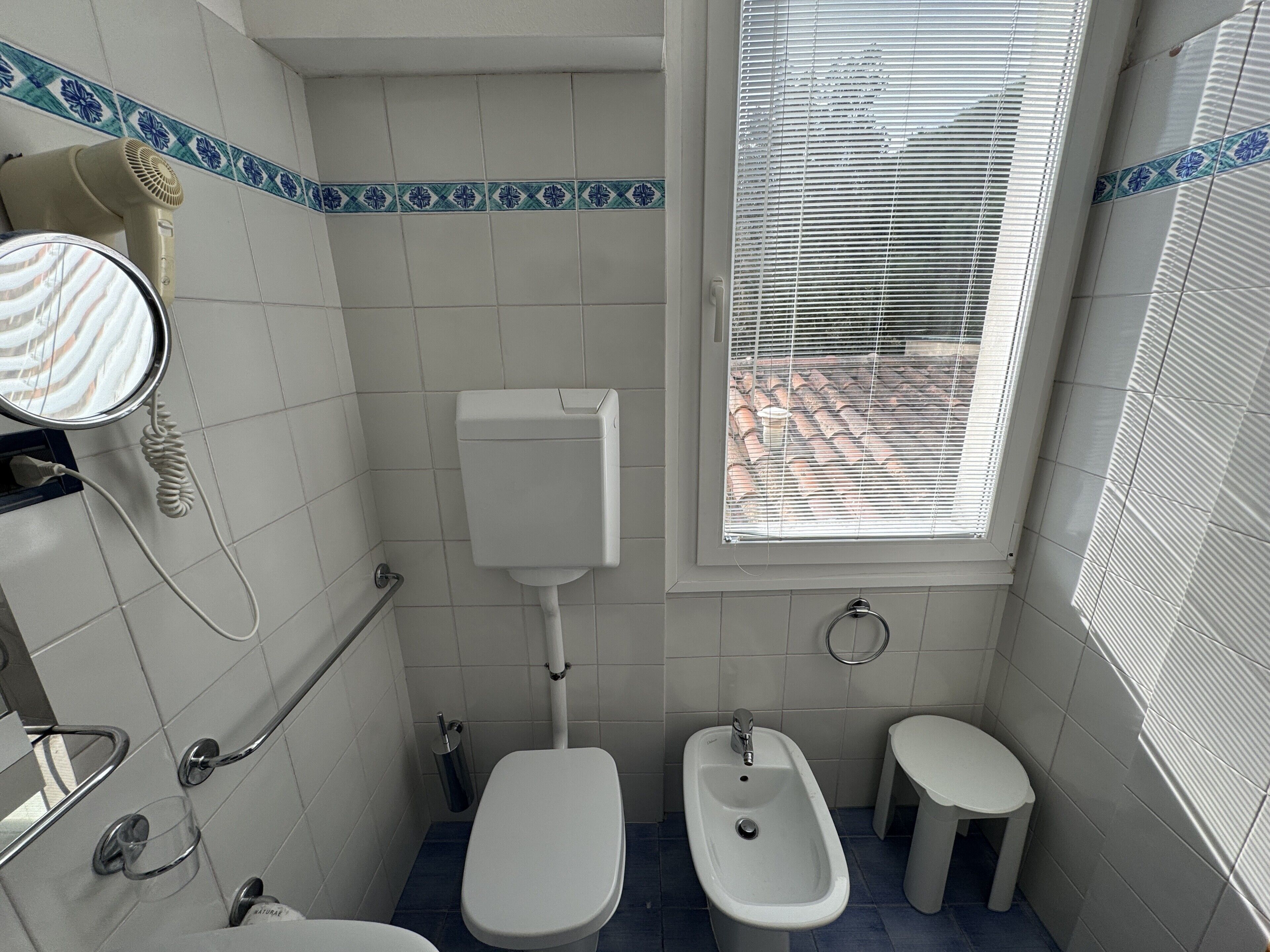 Un bagno con il water, un bidet e una finestra con persiane.