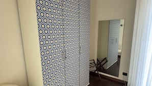 Une pièce avec un paravent à motifs, une chaise blanche, un plancher en bois et un miroir au mur.