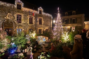 A historic building with stone walls and multiple windows, adorned with festive lights and decorations. - Villa (Malansac)