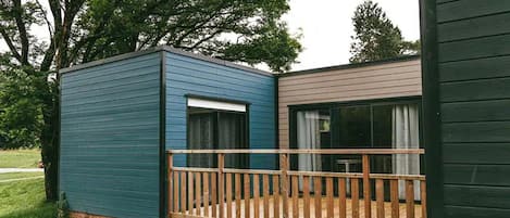A small cabin with a wooden deck and a large window.