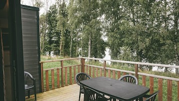 A wooden deck with a table and chairs, overlooking a forested area.
