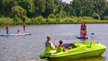 People on watercraft on a calm lake surrounded by greenery.