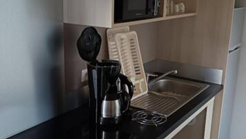 Una kitchenette equipada con cafetera, microondas y pileta.