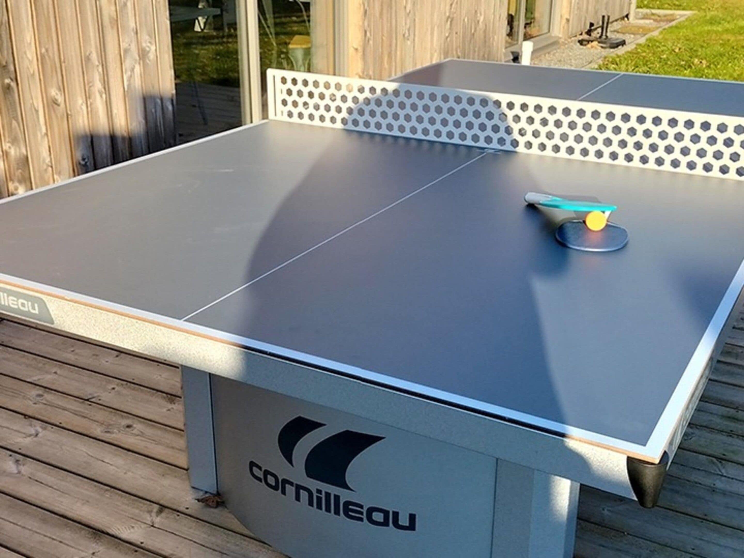 A tabletop ping pong table with a logo, a net, and a ball on it.