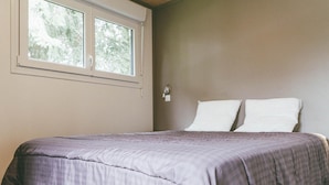 A bedroom with a bed, a window, and a wall-mounted light. - Villa (Malansac)