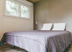 A bedroom with a bed, a window, and a wall-mounted light. - Villa (Malansac)