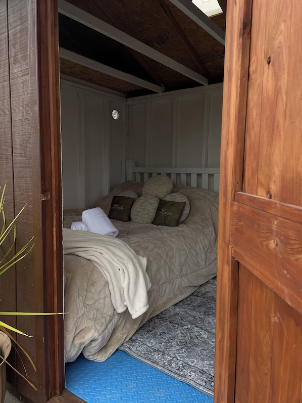 Un dormitorio con una cama, almohadas, una colcha y un tapete azul.