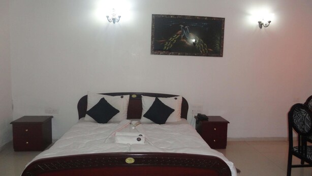 Quarto com cama, mesas de cabeceira, uma cadeira e luminárias na parede.