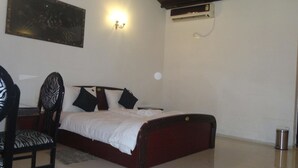 Quarto com cama, cadeira, ar condicionado na parede e um quadro.